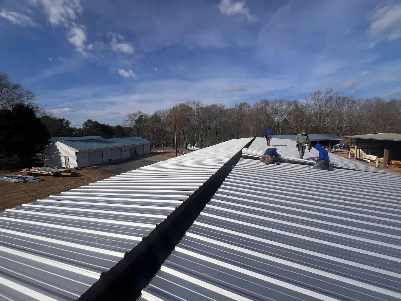 Crew installing standing seam metal roofing on a commercial building