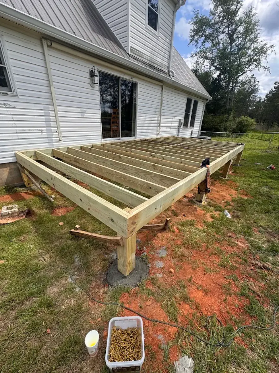 New deck framing under construction behind a home